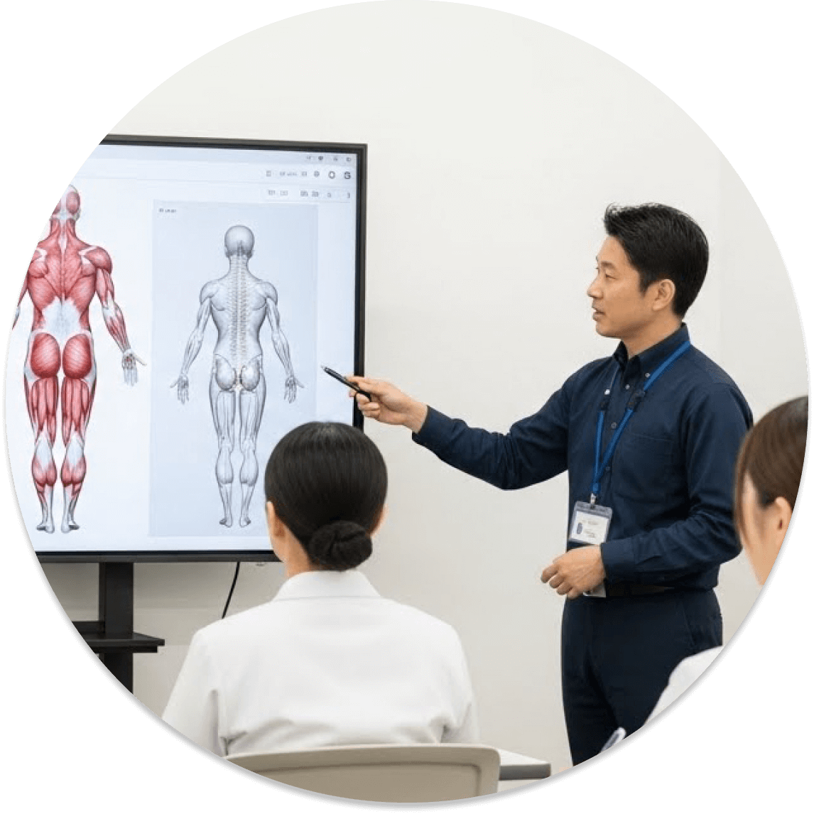 講師が解剖学の資料を使って受講者に説明している場面